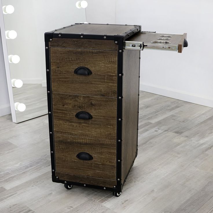 a wooden cabinet with three drawers in front of a mirror and light bulbs on the wall