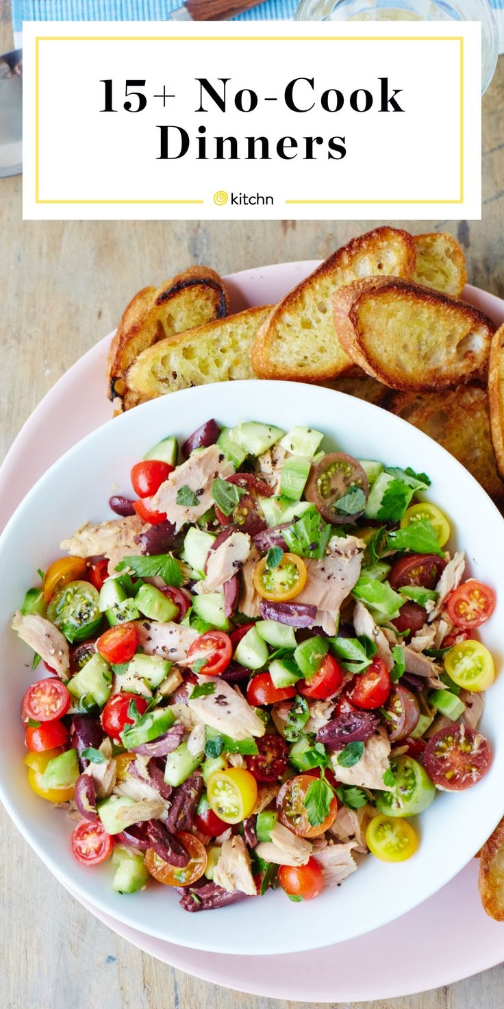 a white bowl filled with salad next to toasted bread on top of a wooden table