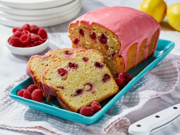 a loaf of raspberry pound cake on a blue plate with raspberries