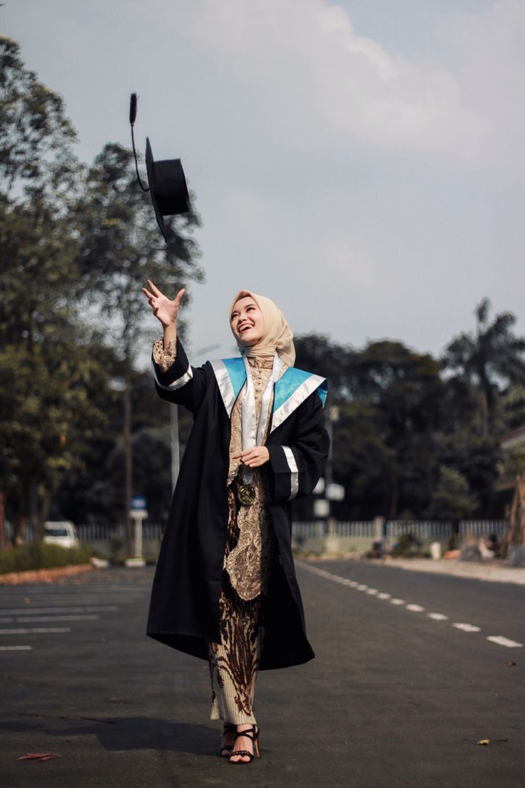 a woman is walking down the street with her graduation cap