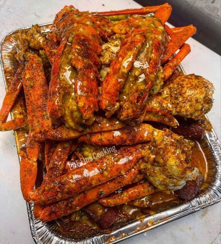 cooked carrots and other vegetables in tin foil on a white counter top with brown sauce