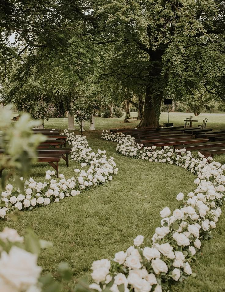 an empty park with benches and flowers in the grass