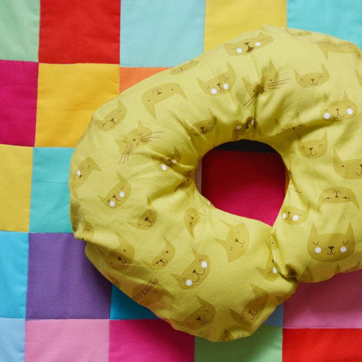 a yellow donut shaped pillow sitting on top of a colorful checkered table cloth