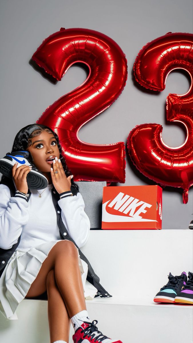 a woman sitting on top of a white bench next to red balloons and nike shoes