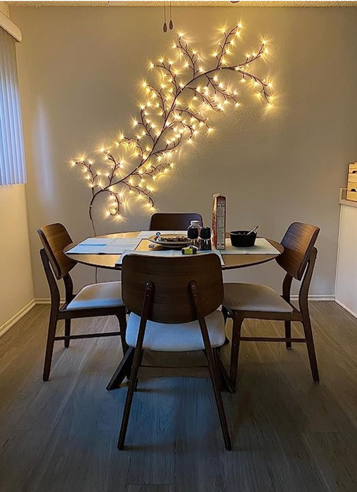 a dining room table and chairs with lights on the wall