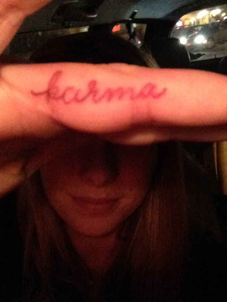 a woman holding her hand up with the word karma written on it in red ink