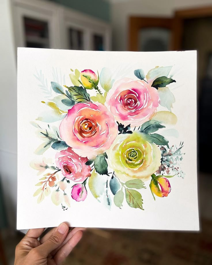 a person holding up a card with watercolor flowers on it