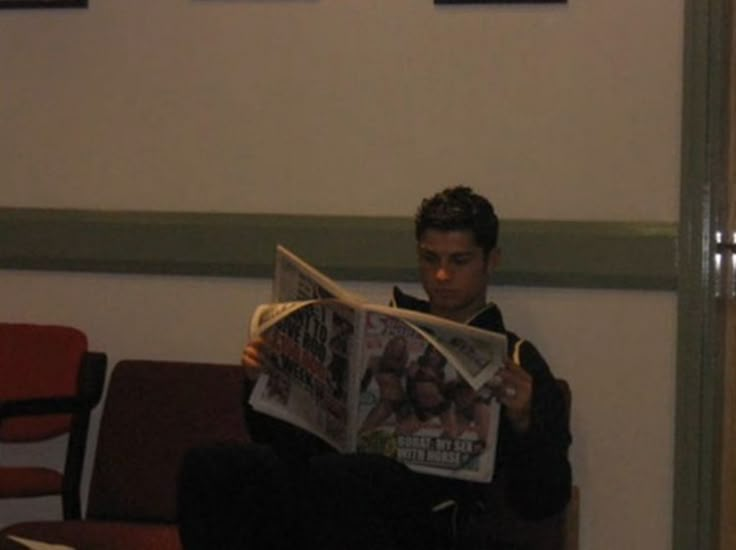 a man sitting in a chair reading a newspaper