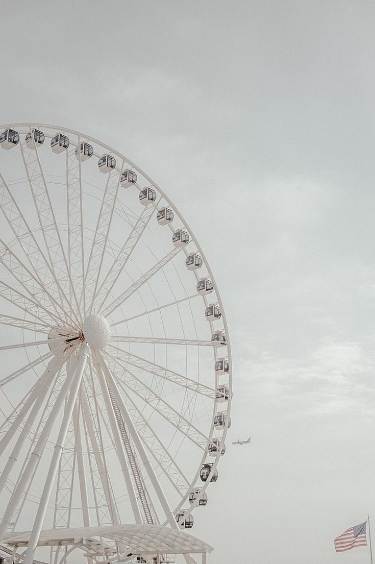 a large ferris wheel sitting in the middle of a field next to an american flag