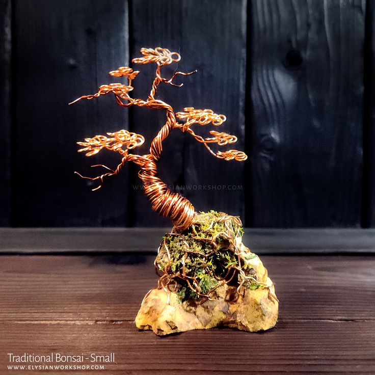 a wire bonsai tree sitting on top of a rock