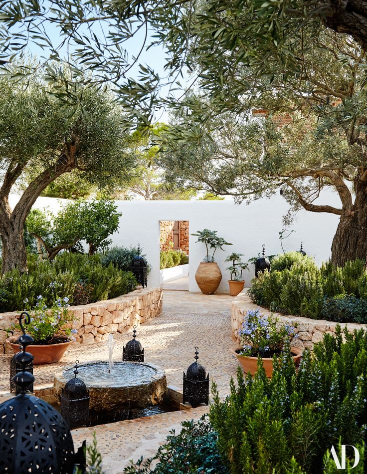 an outdoor courtyard with potted plants and trees in the foreground, surrounded by stone walls