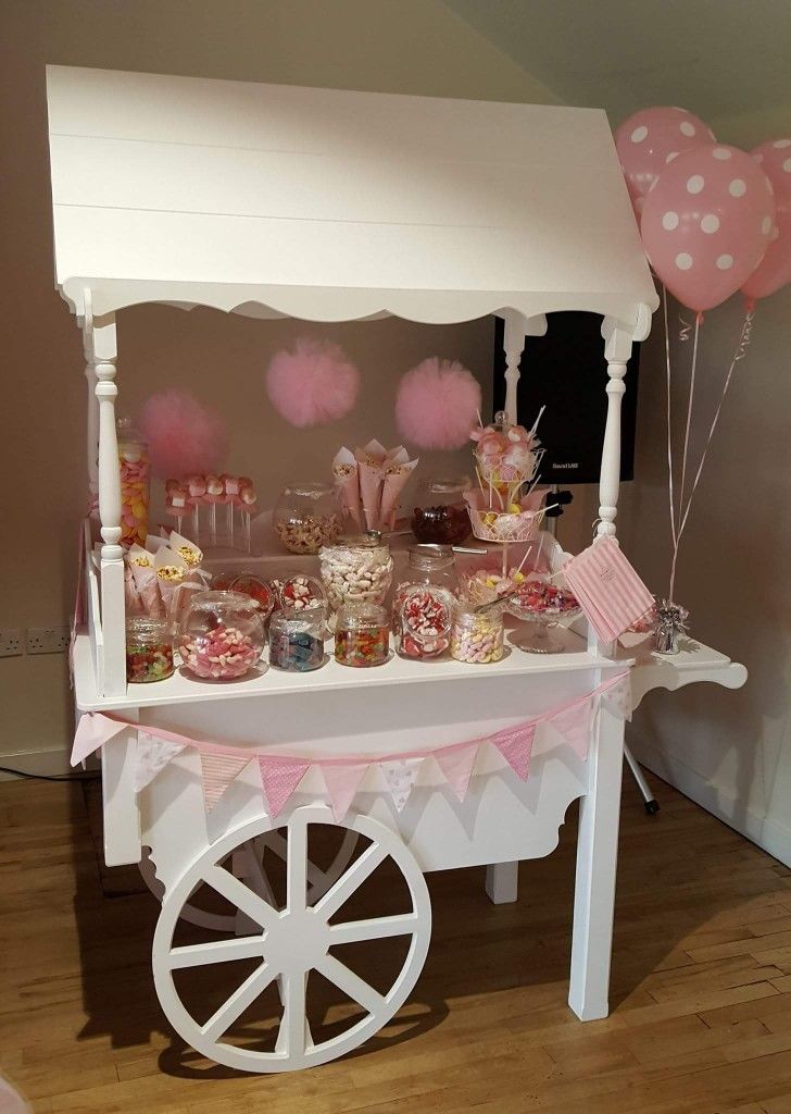 a candy cart with pink and white balloons on it's sides, filled with sweets