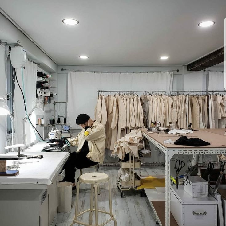 a man sitting on a stool in front of a workbench and sewing machine