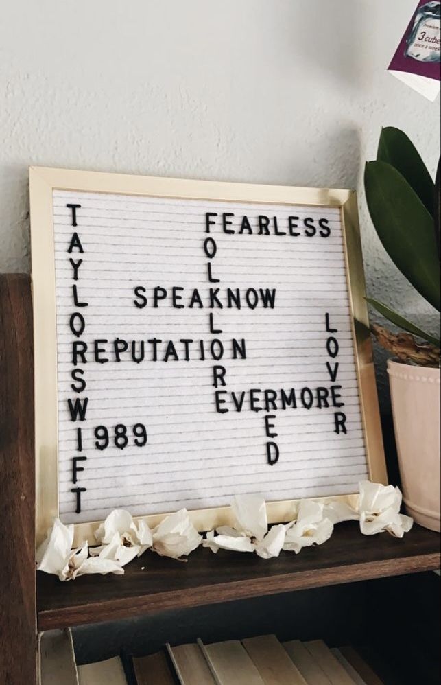 a sign with words written on it sitting next to a potted plant and books