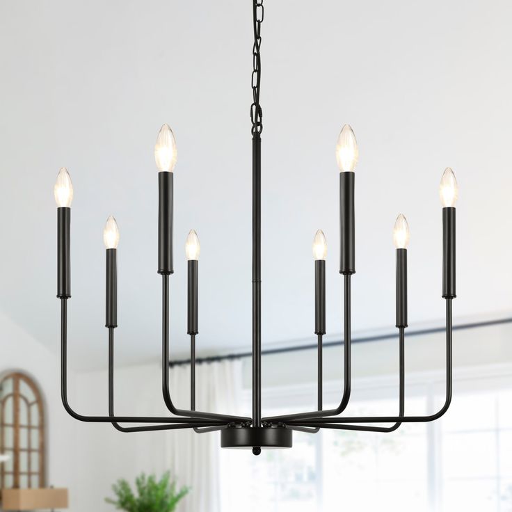 a black chandelier with eight candles hanging from it's centerpiece in a dining room