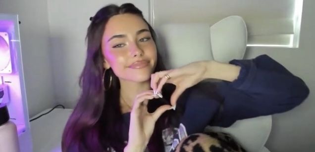 a woman with long purple hair is sitting on an airplane and holding her hand up to her ear