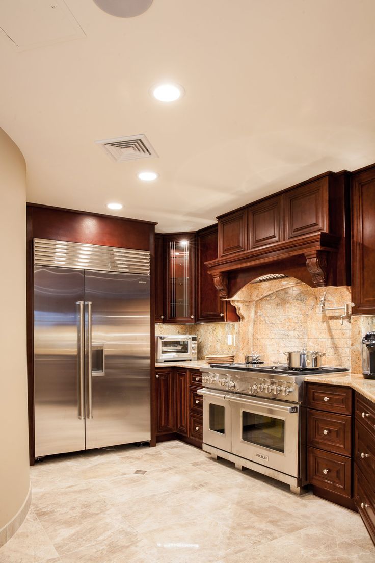 a large kitchen with stainless steel appliances and wooden cabinets, along with marble counter tops