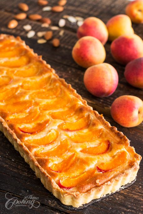 a piece of pie sitting on top of a wooden table next to some peaches