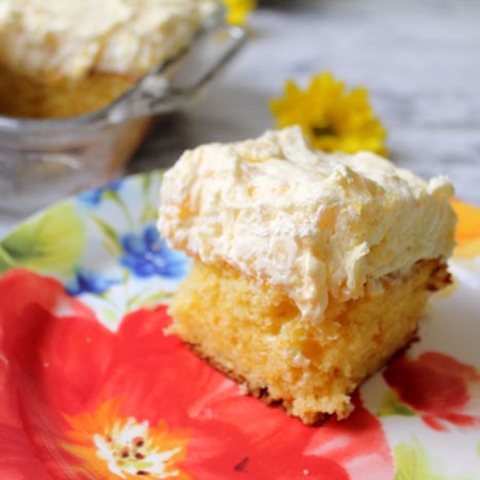 a close up of a piece of cake on a plate with flowers and a cupcake in the background