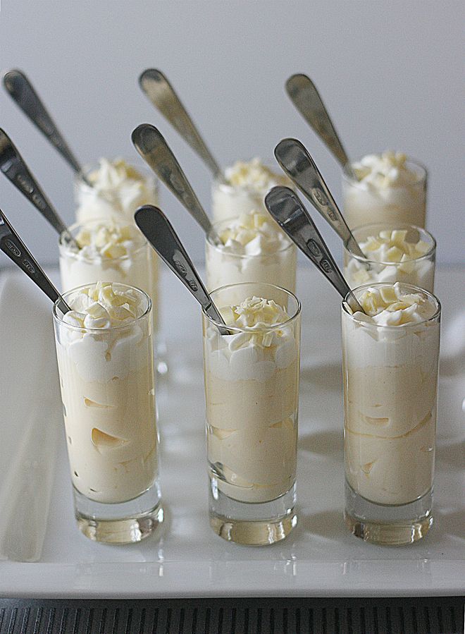 there are many desserts on the tray with spoons in each glass and one is filled with ice cream