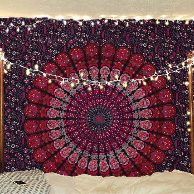 a large red and black tapestry hanging on the wall next to a bed with pillows