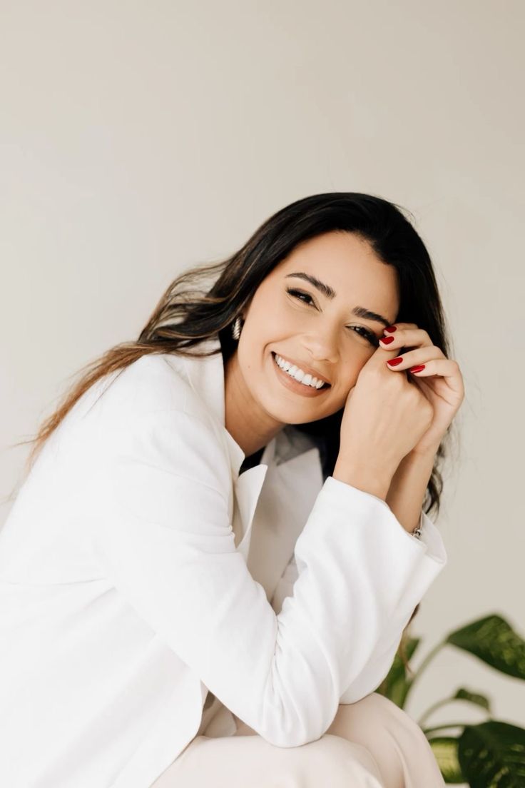 a woman sitting on top of a white couch next to a green potted plant