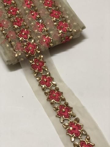 a pair of red and gold bracelets on a white surface with some beads attached to it