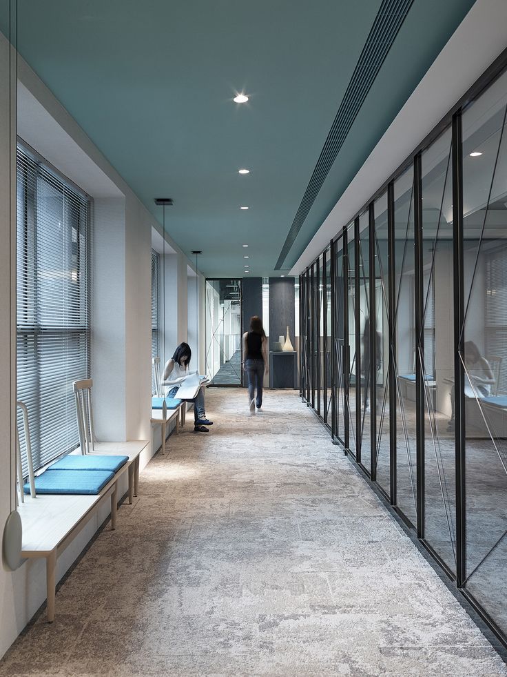 a long hallway with glass walls and benches