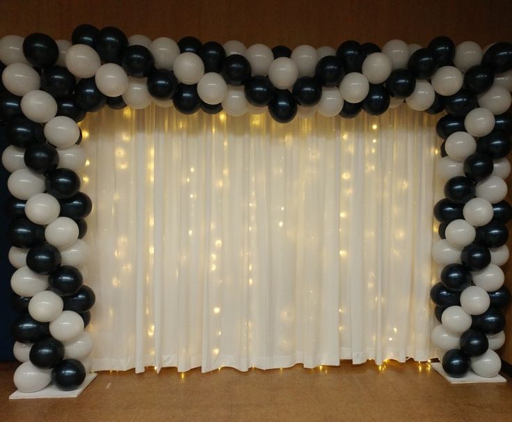 the balloon arch is decorated with black, white and silver balloons for an elegant look