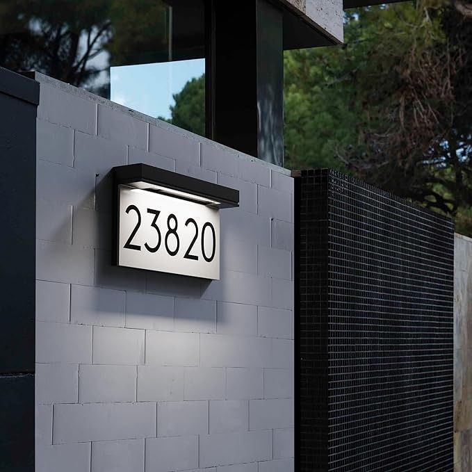 a black and white brick wall with a house number sign on it's side