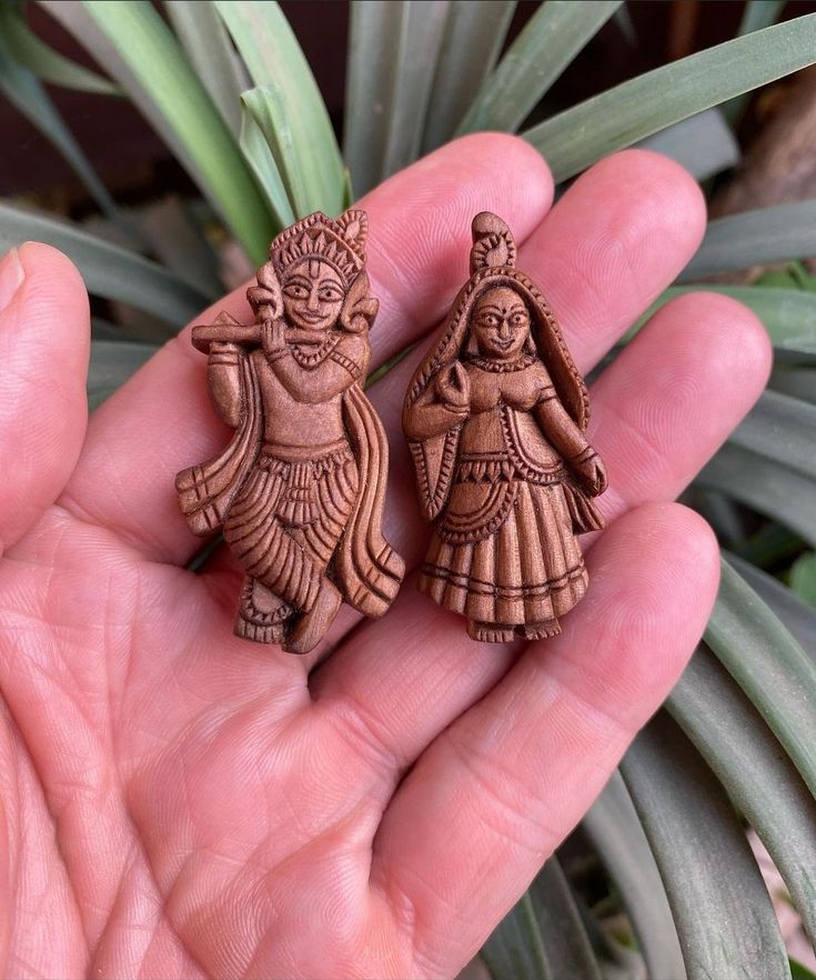 two wooden figurines in the palm of someone's hand