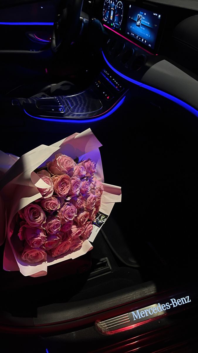 a bouquet of pink roses sitting on top of a car dashboard