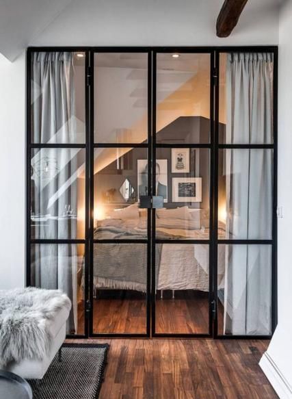 a bedroom with wooden floors and glass doors