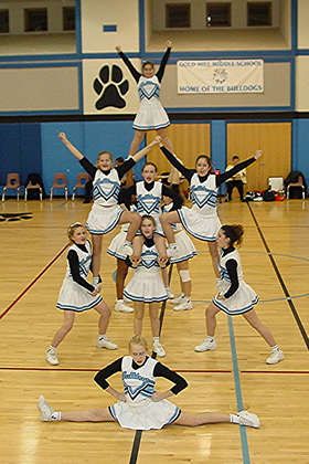 a group of cheerleaders standing in the middle of a basketball court with their hands up