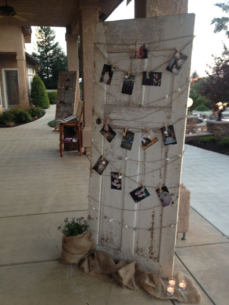 an old door is decorated with photos and twine string lights on the front porch