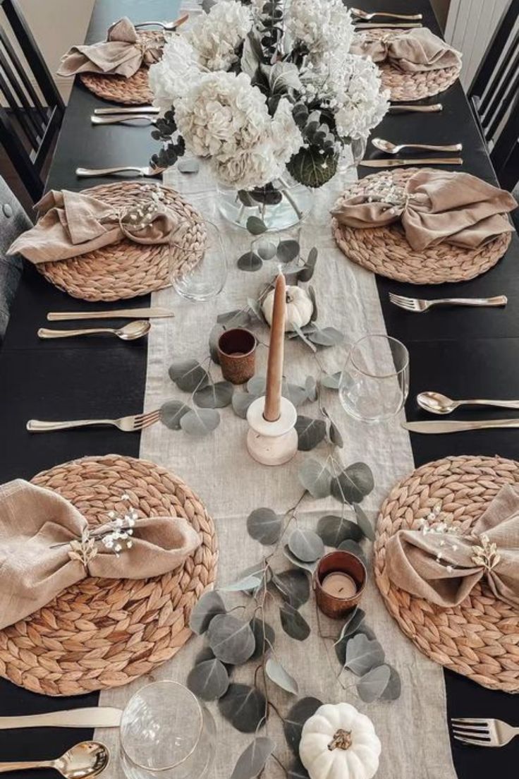 the table is set with black and white plates, napkins, silverware and flowers