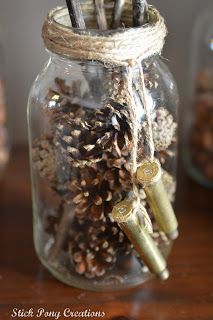 a glass jar filled with pine cones and other items on a wooden table next to jars