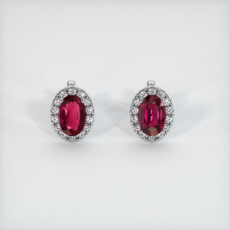 The earrings feature a beautiful, transparent pair of rubies that are 2.92 total carat weight. They are oval shape purplish red rubies, with the dimensions of 8.11 x 5.29 x 4.14 mm and are mixed brilliant cut, have a clarity grade of very slightly included (evaluated at eye level), vivid color saturation, and an excellent polish. #earstuds #earringsstuds #diyearring #earjewelry #earringsjewelry Red Oval Halo Design Earrings, Oval Ruby Earrings With Halo Design, Red Ruby Earrings With Halo Setting, Red Oval Ruby Earrings, Classic Ruby Earrings With Halo Setting, Oval Red Ruby Earrings, Red Ruby Earrings, Cute Ear Piercings, Ruby Earrings