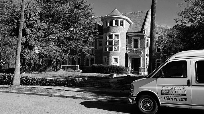 a van is parked in front of a large house with a tower on the corner