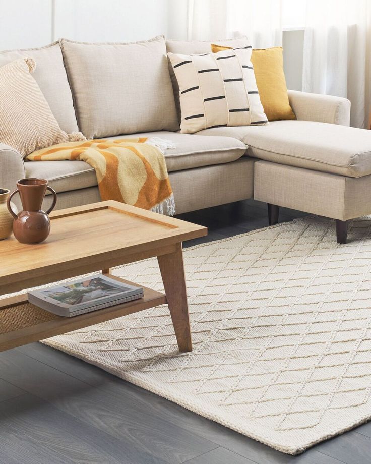 a living room with a couch, coffee table and rug on the floor in front of it