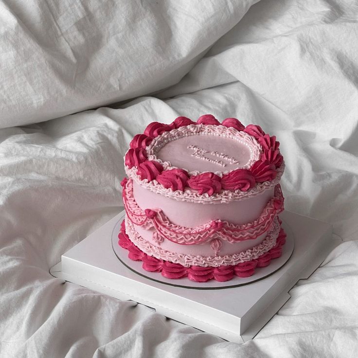 a pink cake sitting on top of a white box