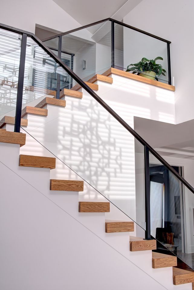 a stair case with glass railing and wooden handrail