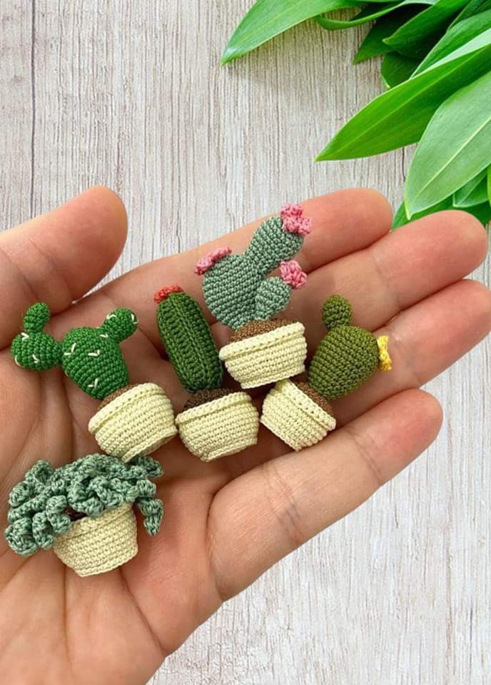 small crocheted cactus plants sitting in someone's hand