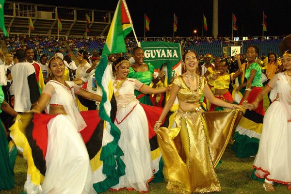 a group of women dressed in colorful outfits and holding flags at a sporting event with people watching