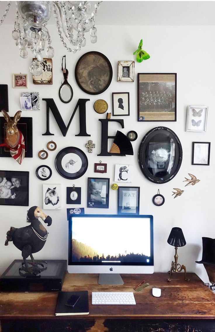 a desktop computer sitting on top of a wooden desk in front of a wall covered with pictures