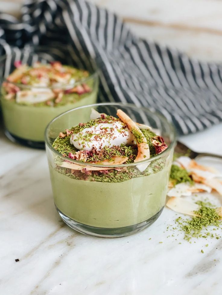 two small bowls filled with food sitting on top of a marble counter next to utensils