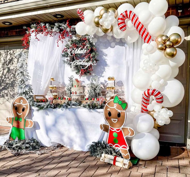 an outdoor christmas party with gingerbread man and woman decorations on the front door, balloons in the shape of candy canes