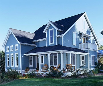 a large blue house sitting on top of a lush green field