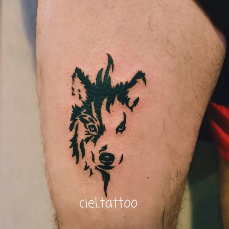 a tattoo on the leg of a man that has a wolf head drawn on it