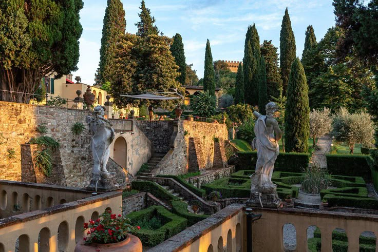 an outdoor garden with statues and hedges